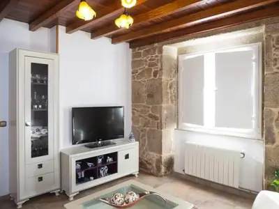 a living room with a television and a stone wall at O Rincón de Mercedes in Jove