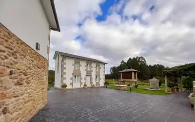 a building with a stone wall next to a courtyard at O Rincón de Mercedes in Jove