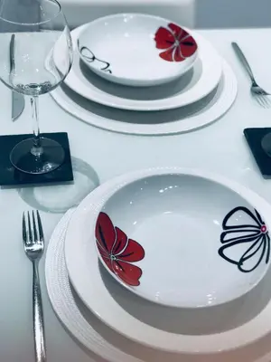 a table topped with white plates with red flowers on them at lucushouse II in Lugo