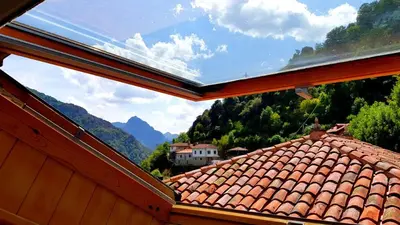 a view from a window of a roof with mountains in the background at zentralclub apartamento El Nido de Somiedo in Santiago del Hermo
