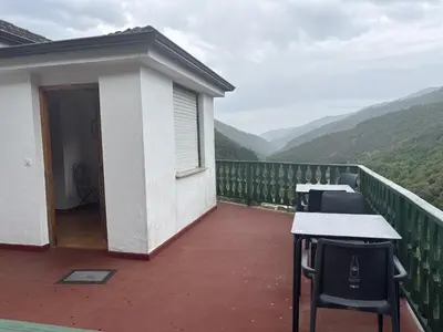 a balcony with tables and chairs with mountains in the background at Hotel rural casa Ferreiro in Seoane