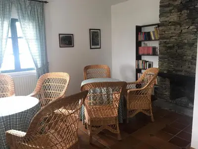 a room with wicker chairs and a table and a fireplace at Hotel rural casa Ferreiro in Seoane