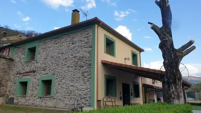 an old stone building with a tree next to it at Casa Rural La Pumarada de Limés in Cangas del Narcea