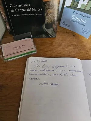 a handwritten letter sitting on a table with books at Casa Rural La Pumarada de Limés in Cangas del Narcea
