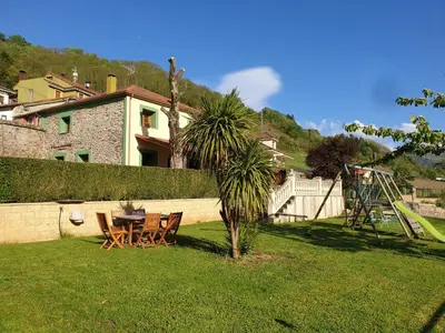 a table and chairs in a yard with a palm tree at Casa Rural La Pumarada de Limés in Cangas del Narcea