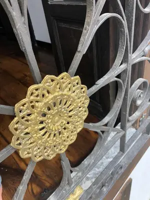 a gold flower decoration on a metal fence at La Capilla del Corral in Cangas del Narcea