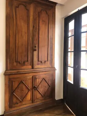 a large wooden cabinet in a room with a window at La Capilla del Corral in Cangas del Narcea