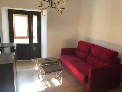 a living room with a red couch and a table at La Capilla del Corral in Cangas del Narcea