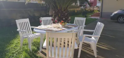 a table with four white chairs and a table with food on it at Casa César in Barreiros