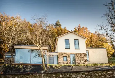 a house in the woods with a stone wall at Eira Gundián in Vedra