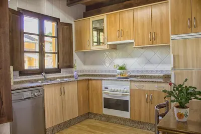 a kitchen with wooden cabinets and stainless steel appliances at casa el susurro in Ponferrada