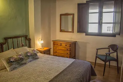 a bedroom with a bed and a dresser and a window at casa el susurro in Ponferrada