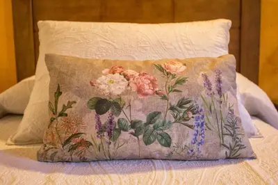 a pillow with flowers on it sitting on a bed at casa el susurro in Ponferrada