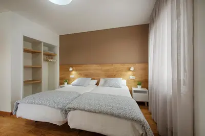 a bedroom with a large bed with white sheets and pillows at Hostal-Restaurante LUGANO in Verín