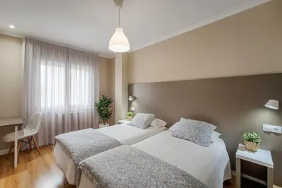 a bedroom with two beds and a table and a chair at Hostal-Restaurante LUGANO in Verín