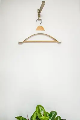 a metal hanger hanging from a white wall with a plant at Hostal-Restaurante LUGANO in Verín