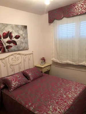 a bedroom with a bed with a red bedspread and a window at Apartamento Playa San Pedro in Barreiros