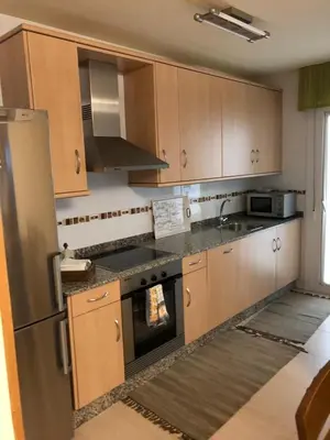 a kitchen with wooden cabinets and a stainless steel refrigerator at Apartamento Playa San Pedro in Barreiros