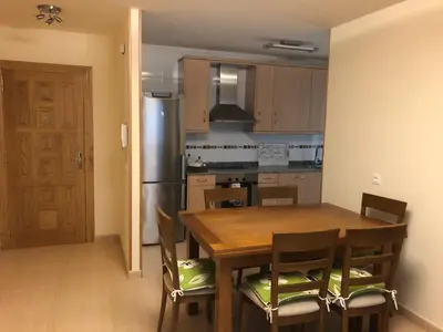 a kitchen with a wooden table with chairs and a refrigerator at Apartamento Playa San Pedro in Barreiros