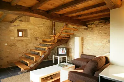 a living room with a spiral staircase in a stone wall at A Parada Das Bestas in Pidre
