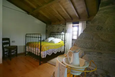 a bedroom with a bed in a stone room at A Parada Das Bestas in Pidre