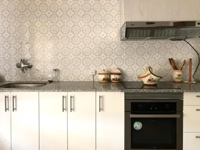 a kitchen with white cabinets and a sink and a stove at Casa de la Abuela in Fabero
