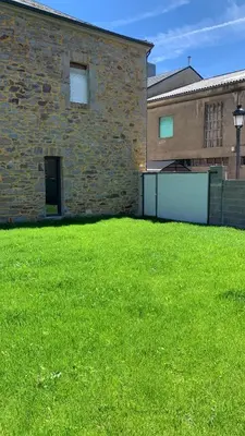 a large grassy yard next to a brick building at Casa de la Abuela in Fabero
