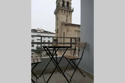 a table and chairs on a balcony with a clock tower at Campania in Ourense