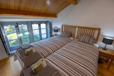 two beds in a room with a couch and windows at Casa Alameda 23 de Casas Das Figueiras en Ría Eo-Ribadeo in Castropol