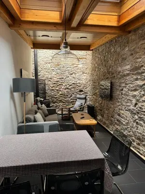 a living room with a table and a stone wall at Casa Alameda 23 de Casas Das Figueiras en Ría Eo-Ribadeo in Castropol