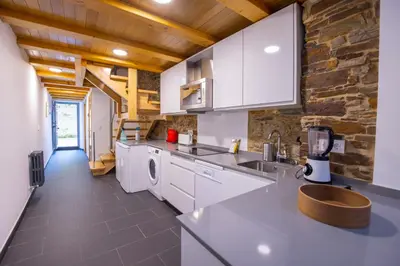 a kitchen with white appliances and a stone wall at Casa Alameda 23 de Casas Das Figueiras en Ría Eo-Ribadeo in Castropol
