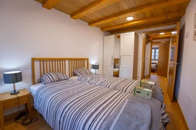 a bedroom with a large bed with striped sheets at Casa Alameda 23 de Casas Das Figueiras en Ría Eo-Ribadeo in Castropol