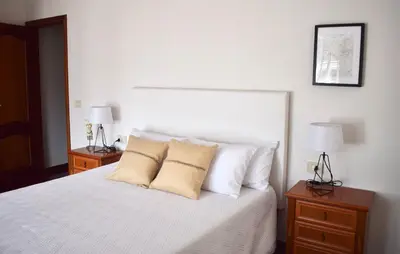 a bedroom with a white bed with pillows and two lamps at Lucus Dúplex in Lugo