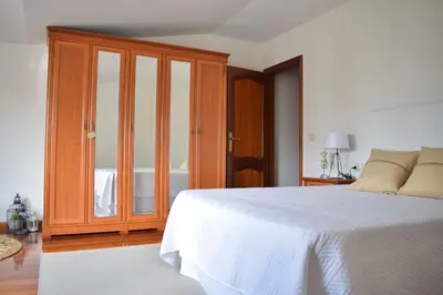 a bedroom with a white bed and a wooden cabinet at Lucus Dúplex in Lugo