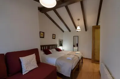 a hotel room with two beds and a couch at Casa rural completa Río Sarela in Santiago de Compostela