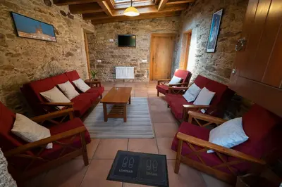 a living room with red chairs and a table at Casa rural completa Río Sarela in Santiago de Compostela