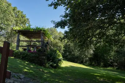 a garden with a wooden structure in the grass at Casa rural completa Río Sarela in Santiago de Compostela