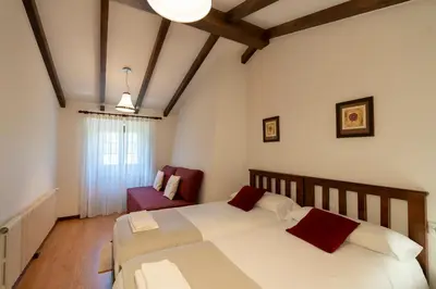 a bedroom with a large white bed and a red chair at Casa rural completa Río Sarela in Santiago de Compostela