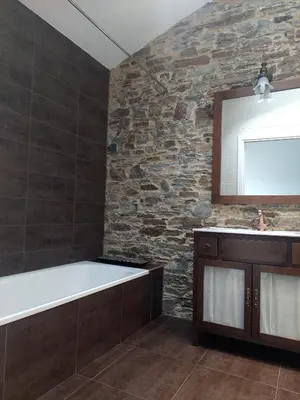 a bathroom with a bath tub and a stone wall at SAN FRANCISCO in Ribadeo