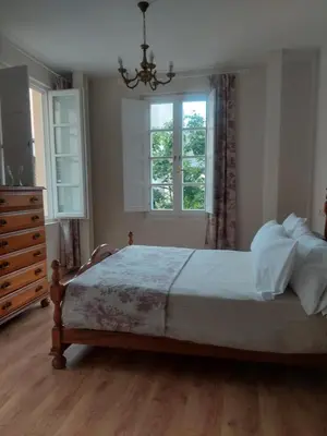 a bedroom with a bed with a chandelier and two windows at SAN FRANCISCO in Ribadeo
