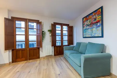 a living room with a blue couch and windows at Apartamentos Moreira & Betanzos in Betanzos