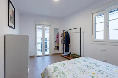 a white bedroom with a bed and a window at Apartamentos Moreira & Betanzos in Betanzos