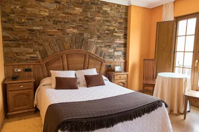 a bedroom with a bed and a stone wall at Hotel Rural Casa Paulino in Taramundi