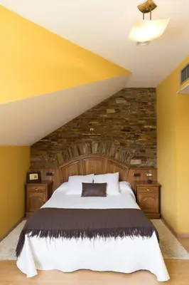 a bedroom with a large bed and a stone wall at Hotel Rural Casa Paulino in Taramundi