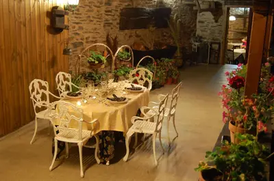 a table with white chairs and a table with flowers at Pacio do Sil in La Rúa