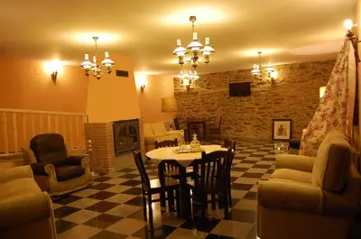 a living room with a table and chairs and a fireplace at Pacio do Sil in La Rúa