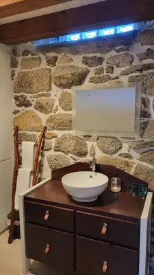 a bathroom with a sink and a stone wall at Vila Morena in Corzos