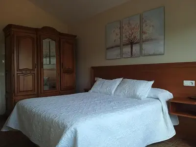 a bedroom with a white bed and a wooden cabinet at Hostal Restaurante O'Cadaval in Frades