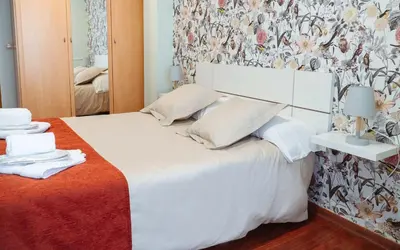 a bedroom with a white bed with a floral wallpaper at A Casa Antiga do Monte Apartamentos Turísticos - Pontecesures in Padrón