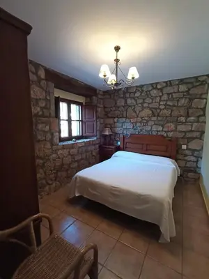 a bedroom with a bed and a stone wall at CASA FELISA in Pola de Somiedo
